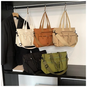 Close-up of multi-pocket canvas tote bag featuring stylish zipper pulls and adjustable straps