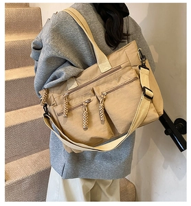 Detail of khaki canvas tote bag featuring multiple zipper pockets and wide shoulder strap