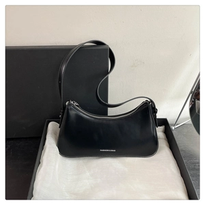 Detail of a black crescent hobo bag made of glossy leather on a white silk cloth background