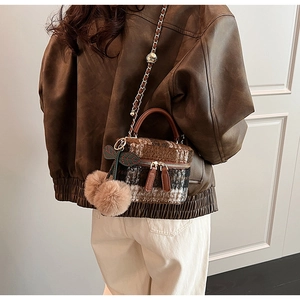 Detail van de wollen geruite mini box bag met gouden ketting en kersen pompom hanger