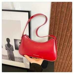 Detail view of red crescent shoulder bag in matte leather with top zipper and slim strap