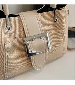 Detailed close-up of apricot woven bucket bag featuring large silver metal square buckle
