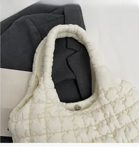 Close-up of white quilted tote bag featuring a magnetic silver buckle and soft texture