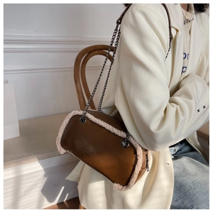 Model wearing a brown leather handbag with white lamb wool trim and metal chain