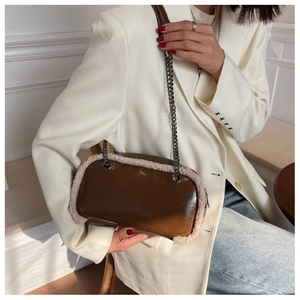 Close-up of brown patent leather handbag with beige faux fur trim and black chain strap
