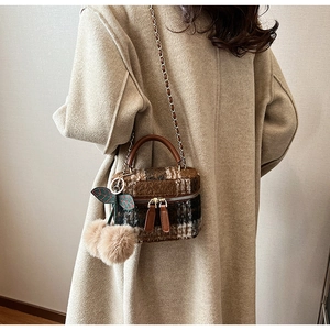 Detail van wollen geruite mini box bag met dubbele ritsen en pluizige kersenhanger accessoire
