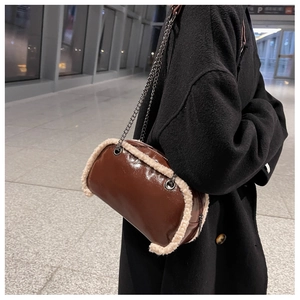 Detail of brown leather bag with white faux fur trim and silver chain shoulder strap