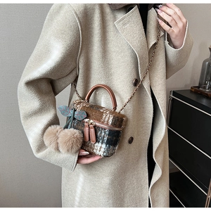 Detail van tweed ruit mini emmer tas met gouden ketting en zachte pluche pompons