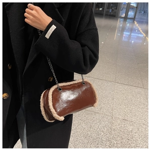 Detail of brown patent leather crossbody bag with cream faux shearling trim and chain strap