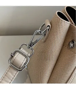 Detail of silver metal hook and adjustable beige leather strap on the woven bucket bag