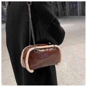 Detail of a brown patent leather shoulder bag with white shearling trim and silver chain