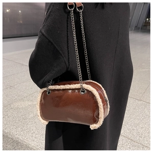 Detail of a brown glossy leather shoulder bag with plush shearling trim and chain strap