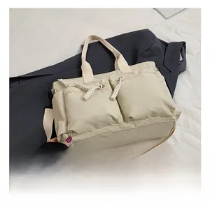 Detail showing cream nylon tote bag with 3D zipper pockets and braided rope pullers