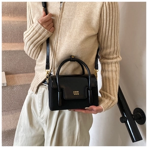Detail of black rectangular crossbody bag featuring mixed leather and gold metal logo