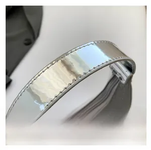 Detail of silver mirror leather handle with precise stitching on fashion crescent bag