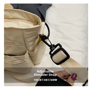 Detail of adjustable nylon shoulder strap with black plastic swivel hook on beige tote bag