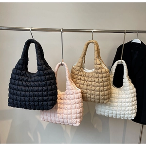 Quilted puffer tote bags in black, pink, tan, and beige hanging for fashion display