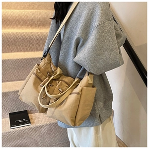 Khaki canvas tote bag detail featuring multiple zip pockets and woven rope zipper pulls