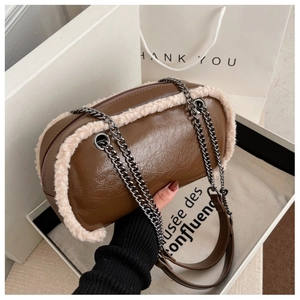Detail view of brown cylinder bag with plush faux fur trim and sleek metal chain strap