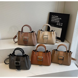 Detail of five stylish trapezoidal bucket bags in neutral tones with silver buckles