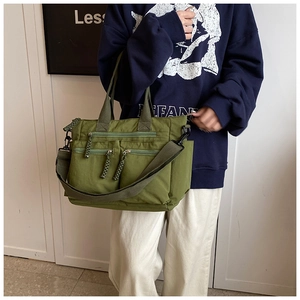 Detailed close-up of army green multi-pocket nylon tote bag with durable woven straps