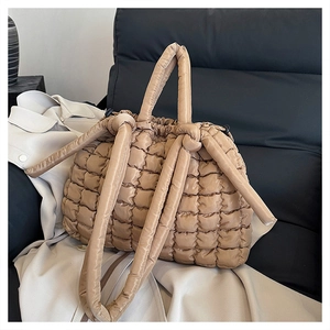 Gros plan du sac cabas matelassé kaki avec nœuds décoratifs sur un trench-coat beige