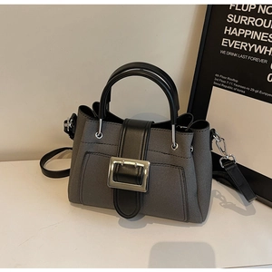 Detail of grey twill fabric handbag with black leather strap and silver metal buckle