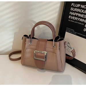 Close-up of khaki bucket bag with textured fabric, silver buckle, and smooth leather trim