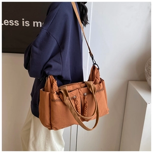 Detail of caramel nylon tote bag showing multiple front zip pockets and woven pullers