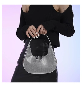 Detail of silver rhinestone hobo bag with dual metal zippers worn by model