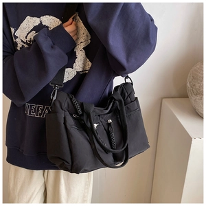 Detail of black canvas tote bag with multi-pocket design and adjustable woven strap