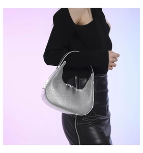 Detail of silver glitter half-moon hobo bag worn over the shoulder by a model