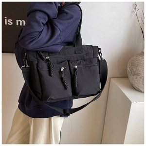 Detail of black nylon tote bag showing utility pockets and adjustable shoulder strap