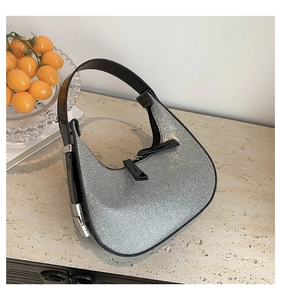 Detailed view of shimmering silver rhinestone crescent bag with black leather handle