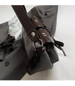 Detailansicht der dunkelbraunen Glanz-Schultertasche mit Silberbeschlägen und Riemen