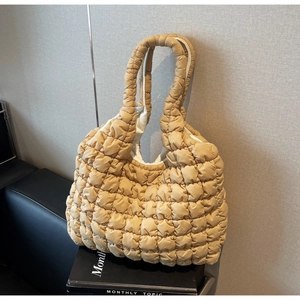 Detail of quilted puffy tote bag with beige textured bubble fabric on a black book
