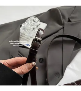 Detail eines verstellbaren dunkelbraunen Leder-Schultergurts mit silberner Schnalle für Taschen