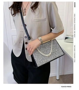 Detail of silver sequin evening bag with pearl handle and black leather shoulder strap