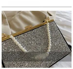 Detailopname van glanzende zilveren pailletten en luxe handvat met parels op de tas