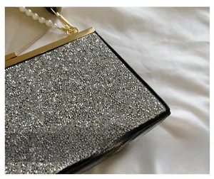 Detail van zilveren strass avondtas met gouden frame en parelmoeren handvat