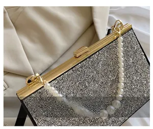 Detail of silver evening bag featuring gold hardware clasp and luxury pearl handle beads