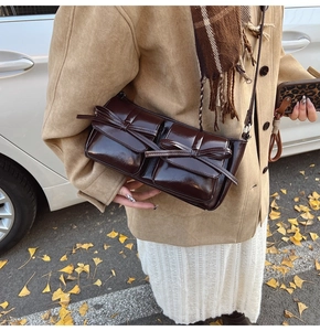 Close-up of vintage dark brown faux leather shoulder bag with bow and double pocket details