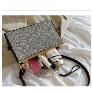 Detail van de binnenruimte van zilveren strass clutch met parelhandvat en schouderband