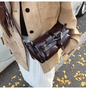 Close-up of vintage brown PU leather shoulder bag with bow details on outdoor background