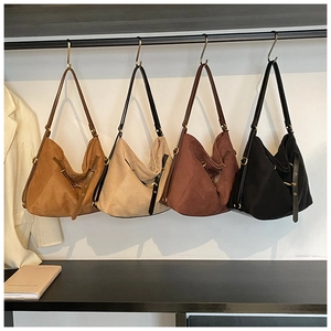 Row of suede tote bags in caramel, beige, coffee, and black hanging on a metal rack