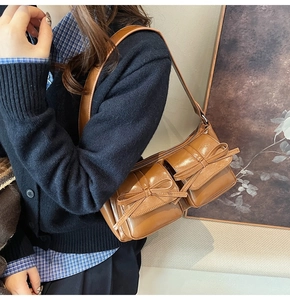 Close-up of brown PU leather shoulder bag featuring bow pockets on a model