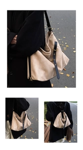 Detail of beige frosted hobo bag with black leather straps and golden metal hardware