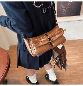 Detailed macro view of the brown bow accents and dual flap pockets on the PU shoulder bag