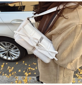 Detail of white PU shoulder bag with dual bow-knot flap pockets and wide strap