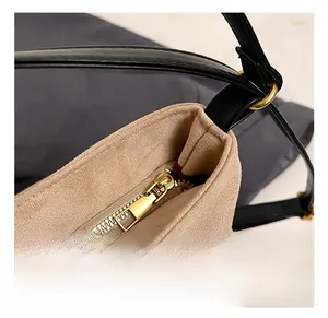 Detail showing high-quality gold metal zipper and suede texture of the shoulder bag